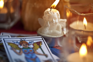 Angel tarot card desk next to multiple candles including a cherub angel candle.