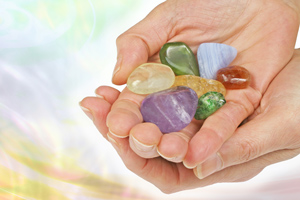 Two cupped hands holding a variety of colorful gemstones.